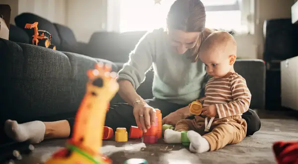 Mama i 7-miesięczne dziecko budują wieżę z kolorowych klocków. Radość i nauka podczas wspólnych zabaw.