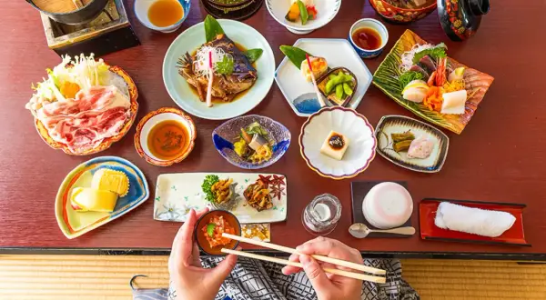 En person njuter av en utsökt japansk måltid med många små rätter, som sashimi, grillad fisk och grönsaker. En härlig upplevelse av japansk street food.