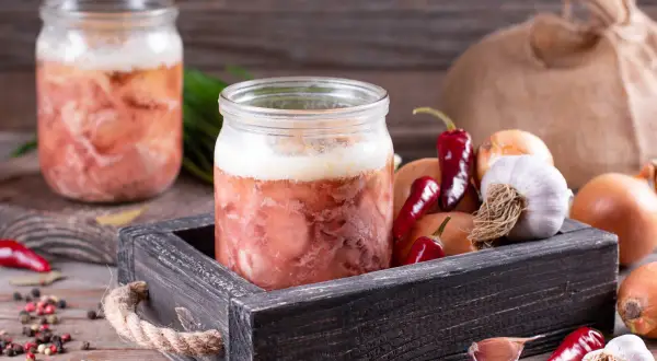 Słoiki z mięsem, idealne do sosu do spaghetti. Obok cebula, czosnek i papryczki chili. Czy można zawekować sos do spaghetti z mięsem? Tak!
