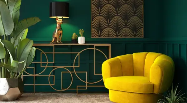 Elegancja w stylu sztuka art deco: złoty kot-lampa, żółty fotel i geometryczne zdobienia na tle butelkowej zieleni.