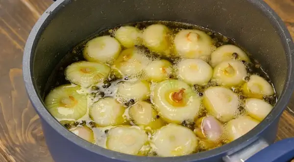 Cipolline in agrodolce in padella con aceto balsamico, che sobbollono in un liquido dorato, pronte per essere gustate.