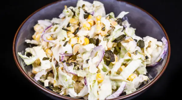 Frischer Chinakohl Salat mit Mais, roten Zwiebeln und Kürbiskernen in cremiger Soße.