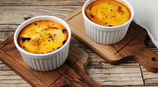 Zwei Portionen Crema Catalana Eis, karamellisiert und auf Holzbrettern serviert.