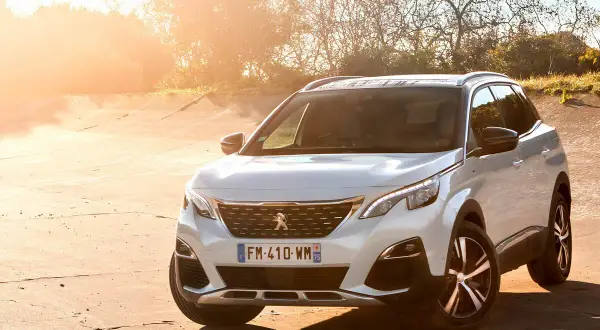 Blanco Peugeot 3008 Hybrid4 aparcado en un camino de tierra al atardecer.