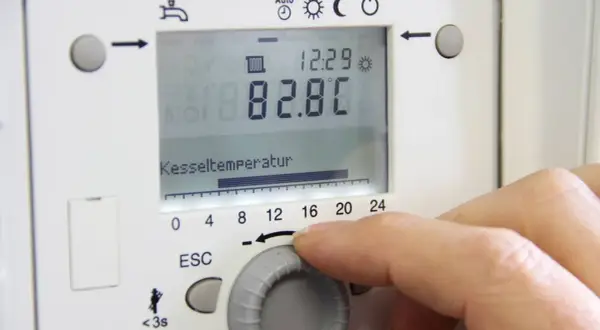 Hand stellt die vorlauftemperatur gasheizung ein. Kesseltemperatur 82.8°C.