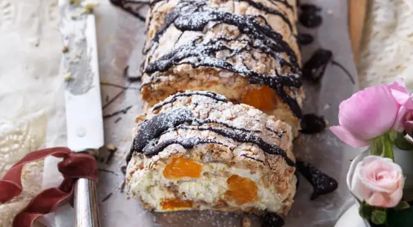 En läcker budapestbakelse med vispgrädde, frukt och chokladdrizzle, pudrad med florsocker.