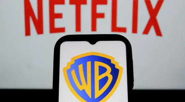Logo Warner Bros. na ekranie telefonu, w tle napis Netflix. Analiza akcji WBD.