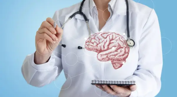 Un médecin en blouse blanche, stéthoscope autour du cou, pointe un cerveau schématisé. Il soigne ce que soigne un neurologue.