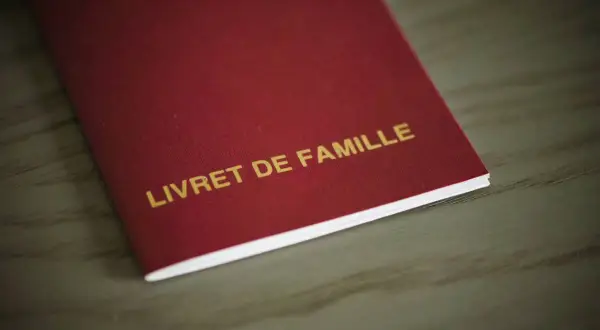 Livre rouge "LIVRET DE FAMILLE" avec mention marginale, document officiel de famille.