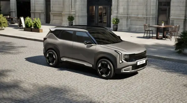 Nowoczesne kia modele, jak ten szary SUV, prezentują się stylowo na brukowanej ulicy przed kawiarnią.