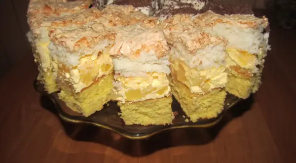 Pyszne ciasto z ananasem i kokosem, z bezą i kremem, pokrojone na kawałki na paterze.