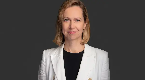Uśmiechnięta kobieta w białej marynarce, profesjonalny terapeuta autyzmu, gotowa do pomocy.