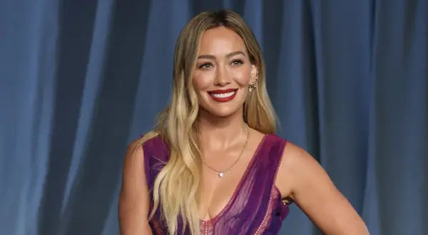 Hilary Duff, bekannt für ihre Filme und Serien, strahlt in einem lila Kleid.