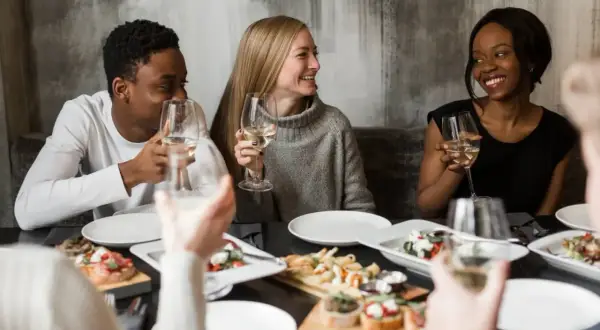 Vänner njuter av middag och vin. Perfekt för att ställa 100 roliga frågor och lära känna varandra bättre.