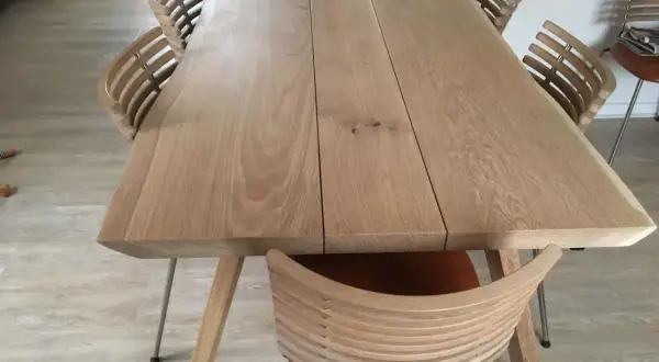 Ett modernt ekbord med en naturlig, pigmenterad oljeyta, omgivet av stilrena stolar med träribbor och lädersits.
