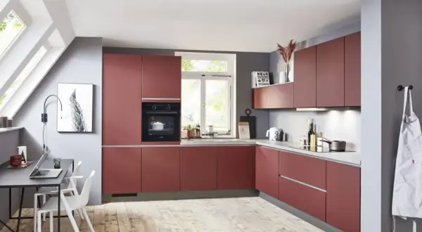 Cocina moderna y alargada con gabinetes rojos, encimeras grises y suelo de madera. Perfecta para distribuir tu espacio.