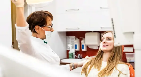 Dentystka przygotowuje się do chirurgicznego usuwania ósemki w ciąży. Pacjentka uśmiecha się, ufając profesjonalistce.