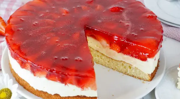 Erdbeerkuchen mit Biskuitboden, Vanillepudding und frischen Erdbeeren unter rotem Tortenguss. Ein saftiges Stück wartet!