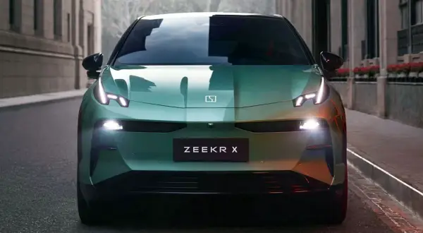 El elegante Zeekr X verde se detiene en una calle urbana, sus luces LED brillan intensamente.