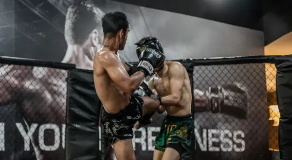 Two fighters in a ring. One lands a kick, likely feeling what does it feel like to get hit in the liver.