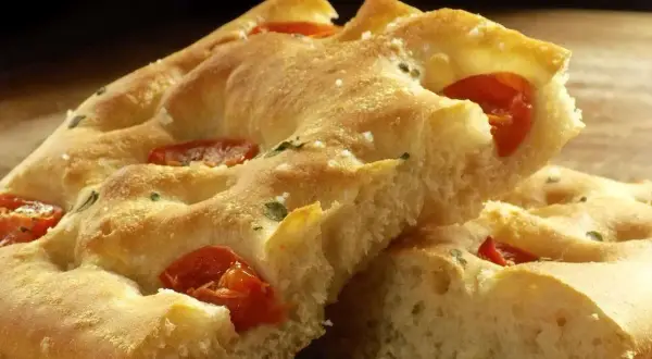 Focaccia moelleuse aux tomates et herbes, un délice qui rappelle la pizza.