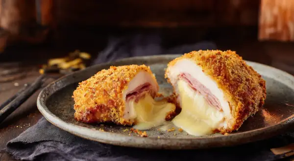 Un cordon bleu coupé en deux, révélant un fromage fondant et du jambon. Le secret d'un bon quel fromage pour cordon bleu réside dans sa texture crémeuse.