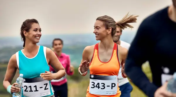 Uśmiechnięte biegaczki na jednym z półmaratonów w Polsce. W tle inni uczestnicy biegu.