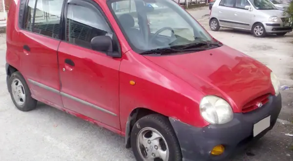 Röd Hyundai Atos parkerad utomhus. En annan silverfärgad bil syns i bakgrunden.