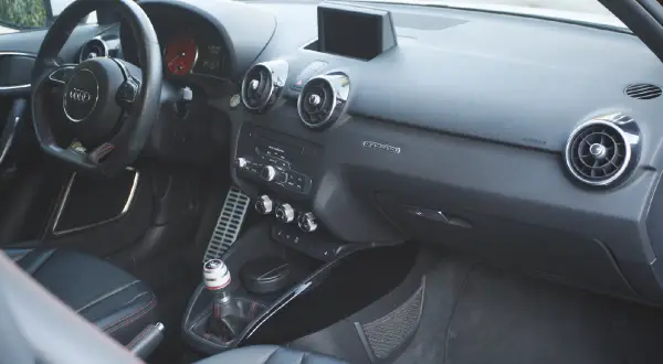 Vue de l'intérieur d'une Audi A1, avec le volant, la console centrale et les sièges en cuir noir.