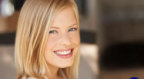 Lächelnde Frau mit blondem Bob, ein moderner **haarschnitt frauen**. Ihr Blick ist strahlend, die Haut makellos.