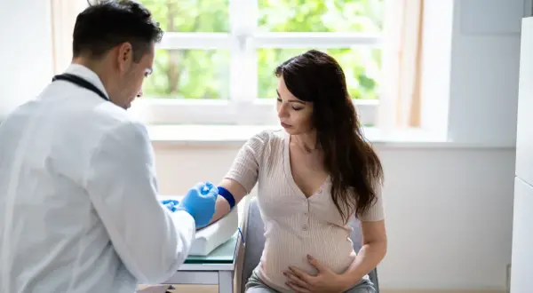Lekarz pobiera krew od ciężarnej kobiety, badając podwyższone neutrofile w ciąży.