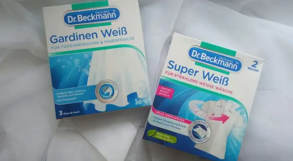 Dwa opakowania Dr. Beckmann do prania białych tkanin. Jedno z nich, "Gardinen Weiß", informuje, że firanki można prać już od 20°C.