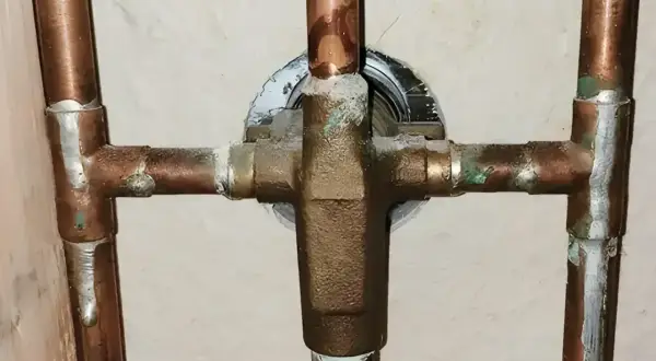 Plomberie en cuivre avec dépôts verts, signe des inconvénients de l'eau trop douce qui corrode le métal.