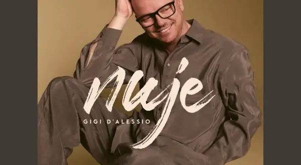 Gigi D'Alessio sorride, con la mano tra i capelli. Sulla sua camicia, la scritta "Nuje". Chissà cosa ci spiegate cherè.