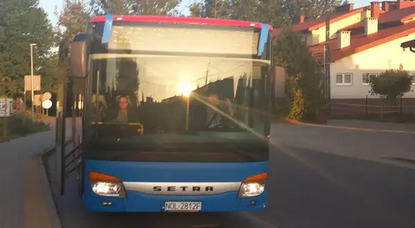 Niebieski autobus Setra z Giżycka do Olsztyna, sprawdzam express bus Giżycko Olsztyn cena. Słońce odbija się w szybie.