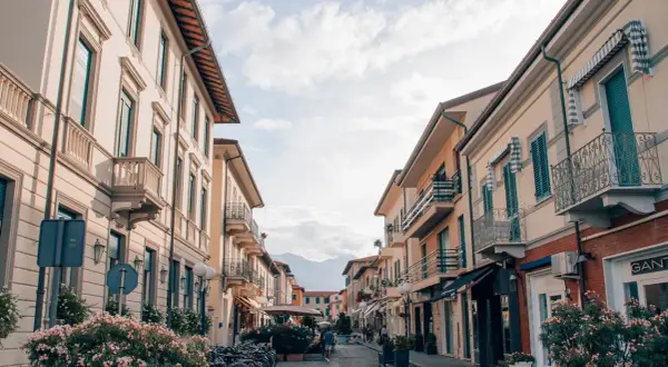 Strada pittoresca a Forte dei Marmi, Italia, con palazzi color pastello, balconi in ferro battuto e biciclette parcheggiate.