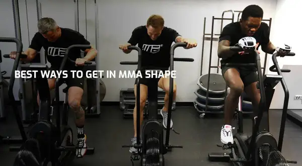 Three men with impressive fighters physique train on air bikes in a gym, showcasing their dedication to peak physical condition.