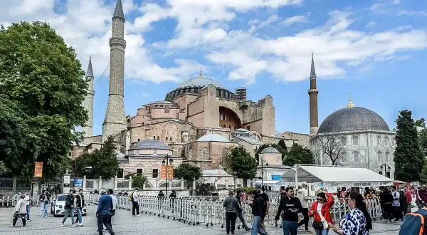 Tłum ludzi spaceruje przed majestatyczną Hagia Sophia w Stambule, podziwiając jej architekturę.