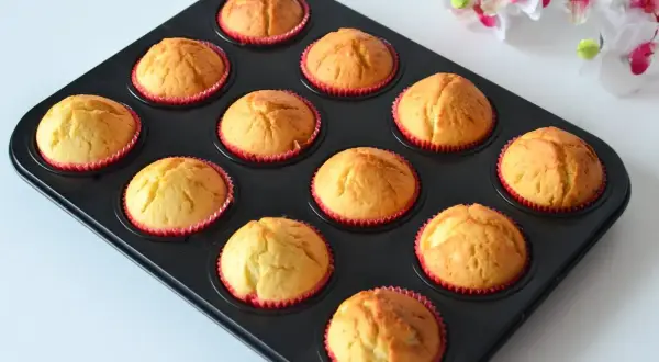 Upieczone, wilgotne muffinki jogurtowe w czerwonych papilotkach, gotowe do jedzenia.