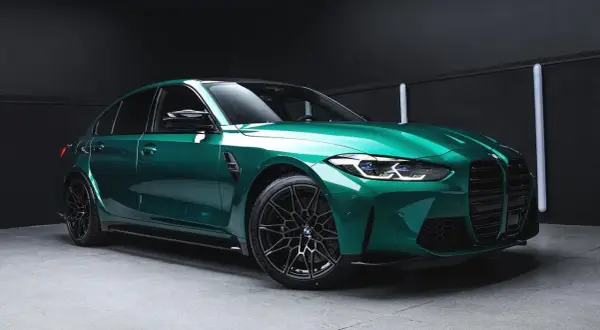 Błyszczący, sportowy sedan w kolorze midnight green, z czarnymi felgami i agresywnym przodem, gotowy na nocne wyścigi.