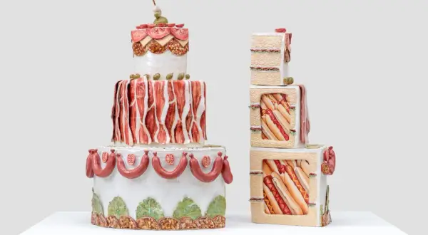 Whimsical Wayne Thiebaud cakes, one a tiered tower of savory meats and olives, the other stacked cubes revealing hot dogs and sandwiches.