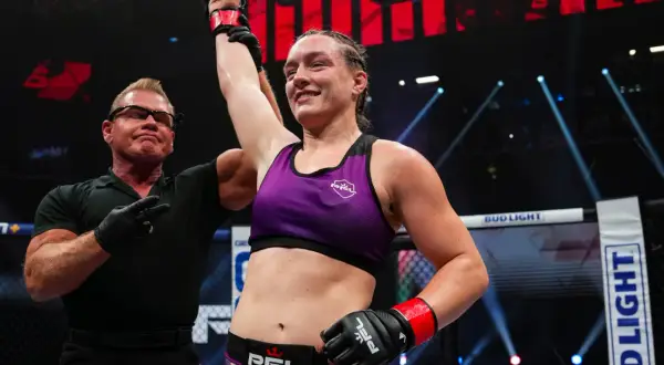 Jessica Rose Clark firar en seger i buren, med domaren som lyfter hennes arm.