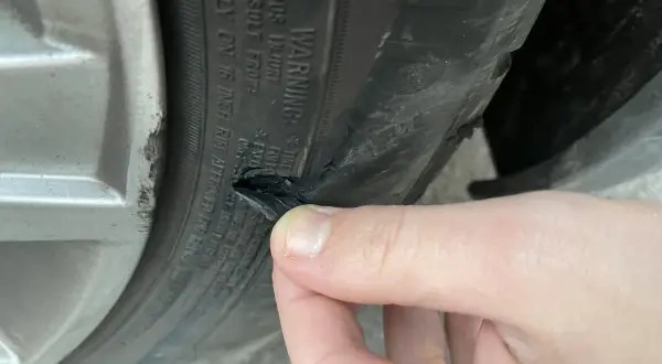 Un pneu abîmé sur le flanc, probablement suite à un choc contre le trottoir. La gomme est déchirée.