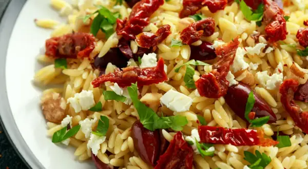 Pyszna sałatka z makaronu orzo, suszonych pomidorów, oliwek, sera feta i świeżej bazylii.