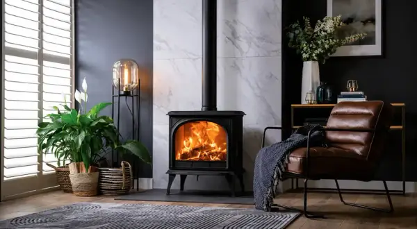 Poêle à bois en fonte, cœur de la pièce, réchauffant l'atmosphère. Un fauteuil en cuir invite à la détente.