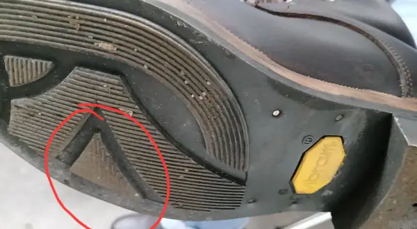 Zużyta podeszwa Vibram w bucie górskim. Czerwone koło wskazuje na uszkodzenie, które może być jedną z przyczyn szybkiego zużycia podeszwy Vibram.