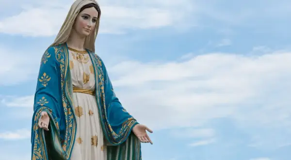 Kamienna figura Matki Bożej w błękitnym płaszczu ze złotymi zdobieniami, jakby wznosiła się do nieba podczas litanii do Matki Bożej.