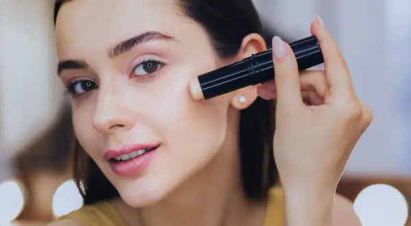 Donna applica il correttore, assicurandosi che il correttore deve essere più chiaro del fondotinta per un look luminoso.