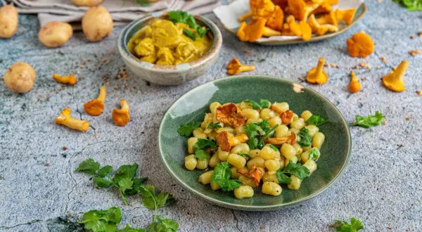 Pyszny obiad z ziemniaków: kluseczki z kurkami i zieloną pietruszką, obok miseczka curry i świeże kurki.