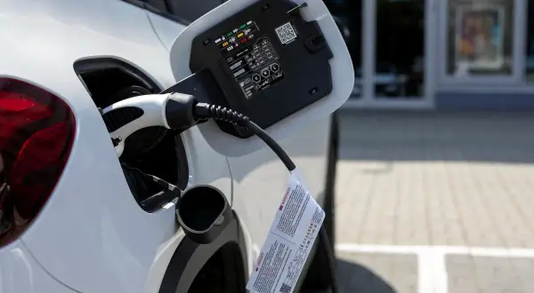 Biały samochód podłączony do ładowania. To przyszłość motoryzacji, czyli przerabianie samochodów na elektryczne.